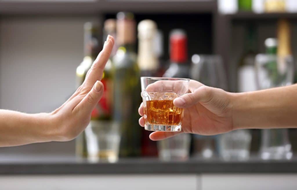 Sober Life - Female hand rejecting glass with alcoholic beverage on blurred background. Pathfinders in Arizona has an Alcohol Rehab program to help you live a sober life.