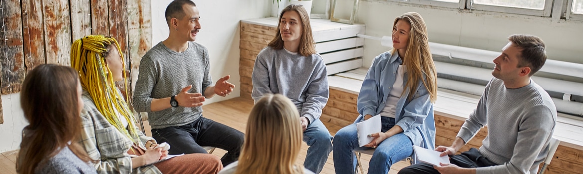Is alcohol a Depressant Pathfinders - A group of people sit in a circle as they discuss coping with triggers during the group therapy session at alcohol rehab.