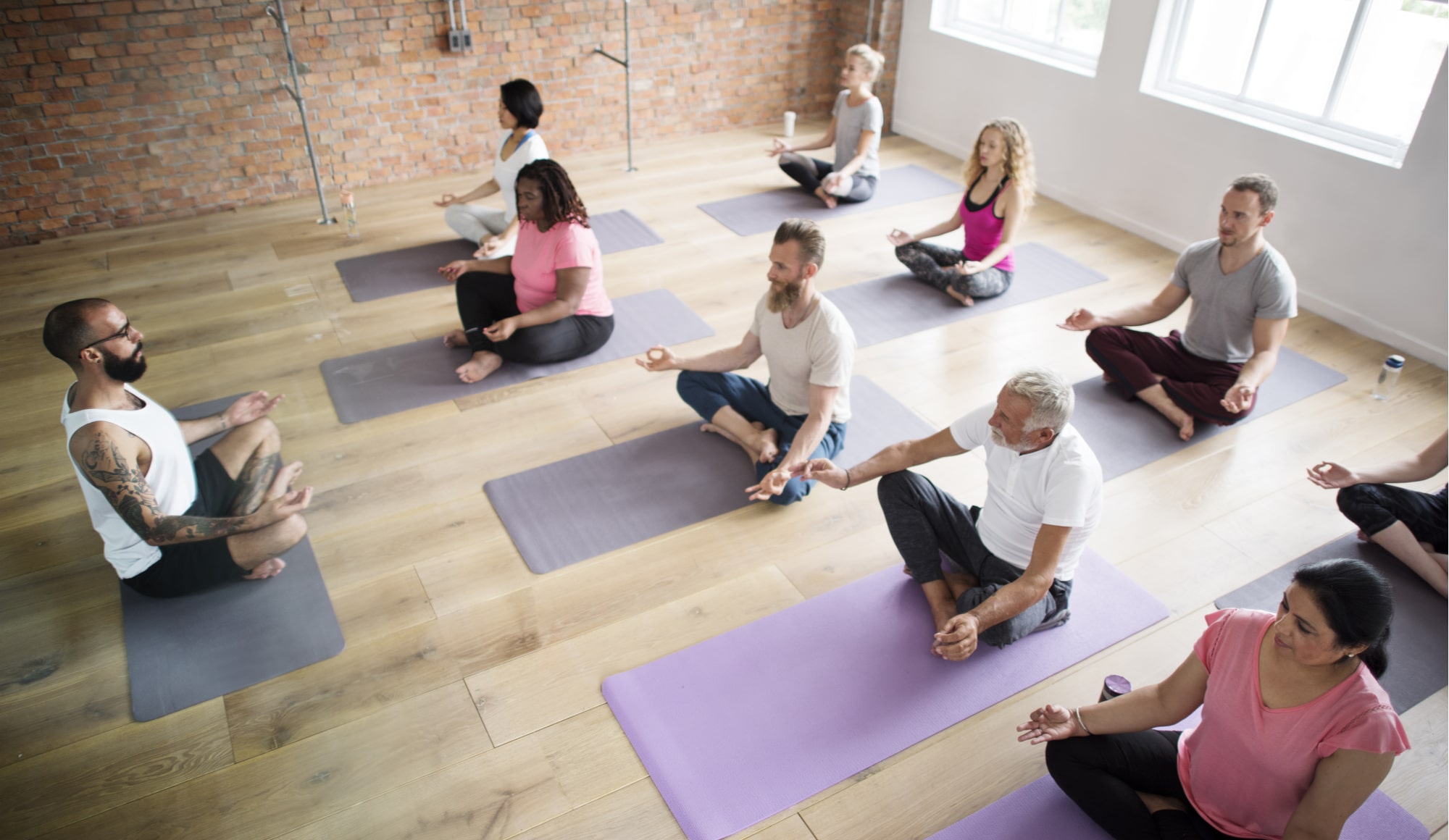 The Amazing Benefits of Yoga for Depression and Anxiety Pathfinders - A group of individuals in recovery are practicing yoga for depression and anxiety, as well as meditation techniques from a professional yoga instructor to help with implementing healthy coping mechanisms, avoid relapse, and build a support system with the individuals in the yoga class.