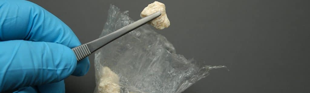 Cocaine Addiction - Close up photo of a piece of Crack being held by a pair of tweezers. Crack is a much cheaper form of cocaine and quickly turns into a cocaine addiction.