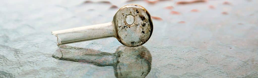 Crack Addiction - Photo of a crack pipe on a glass table. Crack addiction is quick to take hold of a user and needs professional help to recover.